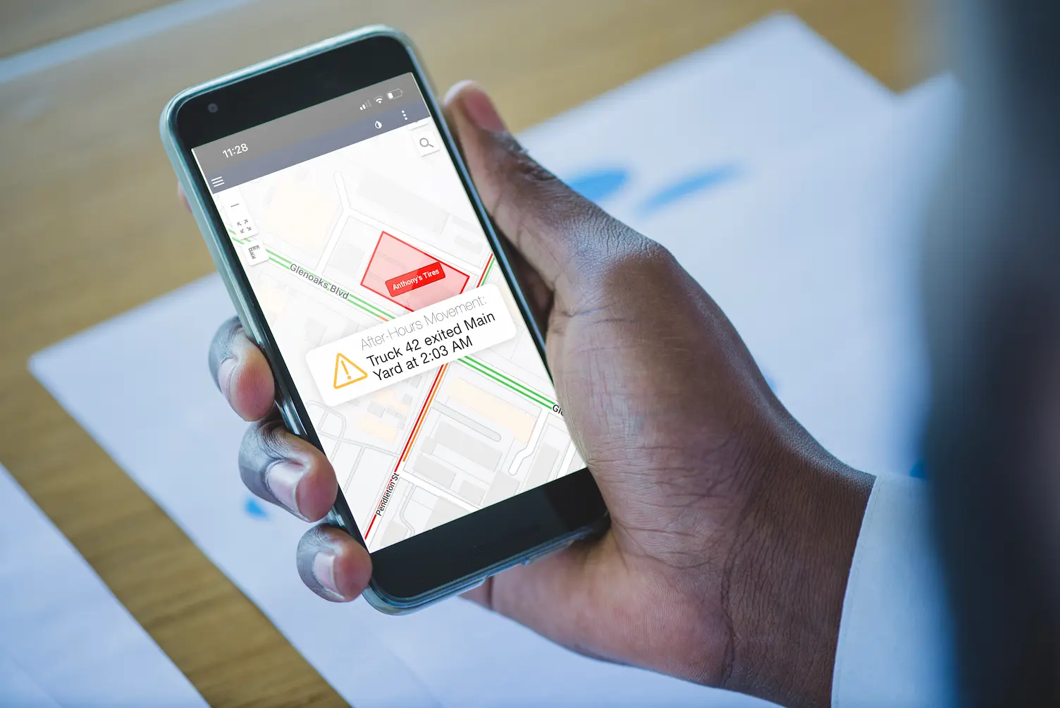 Mobile phone displaying a geofence alert notification for after-hours vehicle movement outside a designated fleet yard