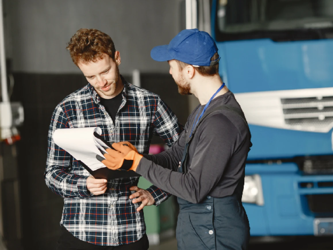 A fleet customer and a One Step GPS rep reviewing paperwork together in front of a truck, illustrating rep-managed onboarding.