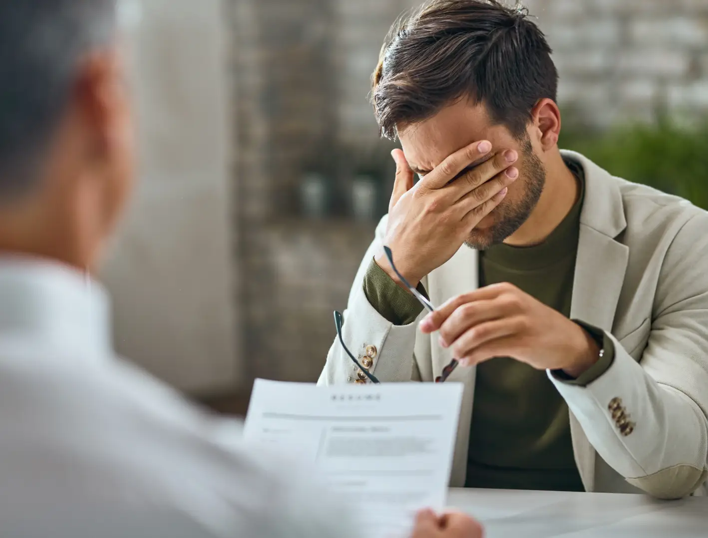 A small-business owner sitting with his hand over his face during a meeting, conveying the everyday frustration of not knowing where his fleet is that this section describes.
