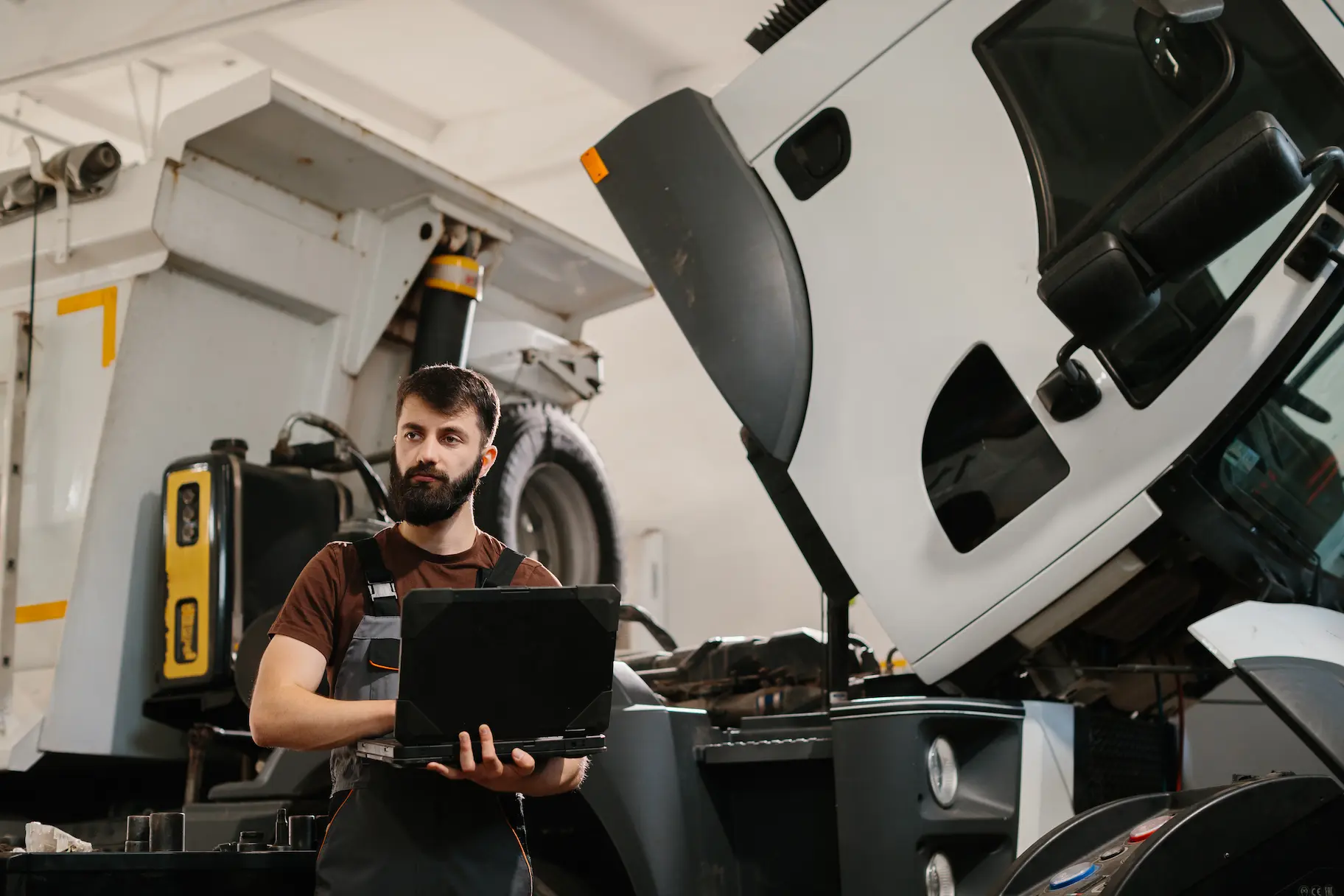 Technician using a laptop to diagnose a commercial truck during maintenance