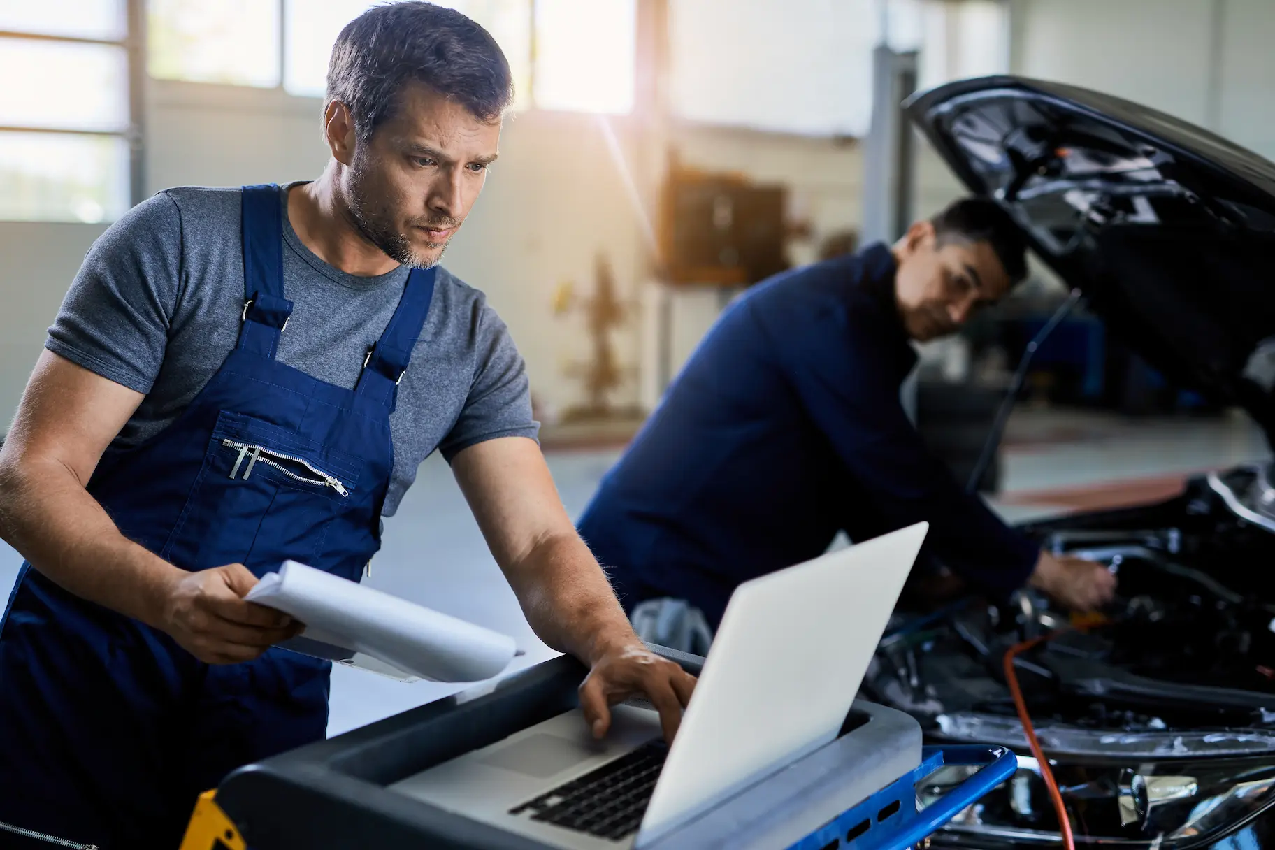 Fleet mechanic reviewing vehicle data on a laptop during maintenance work