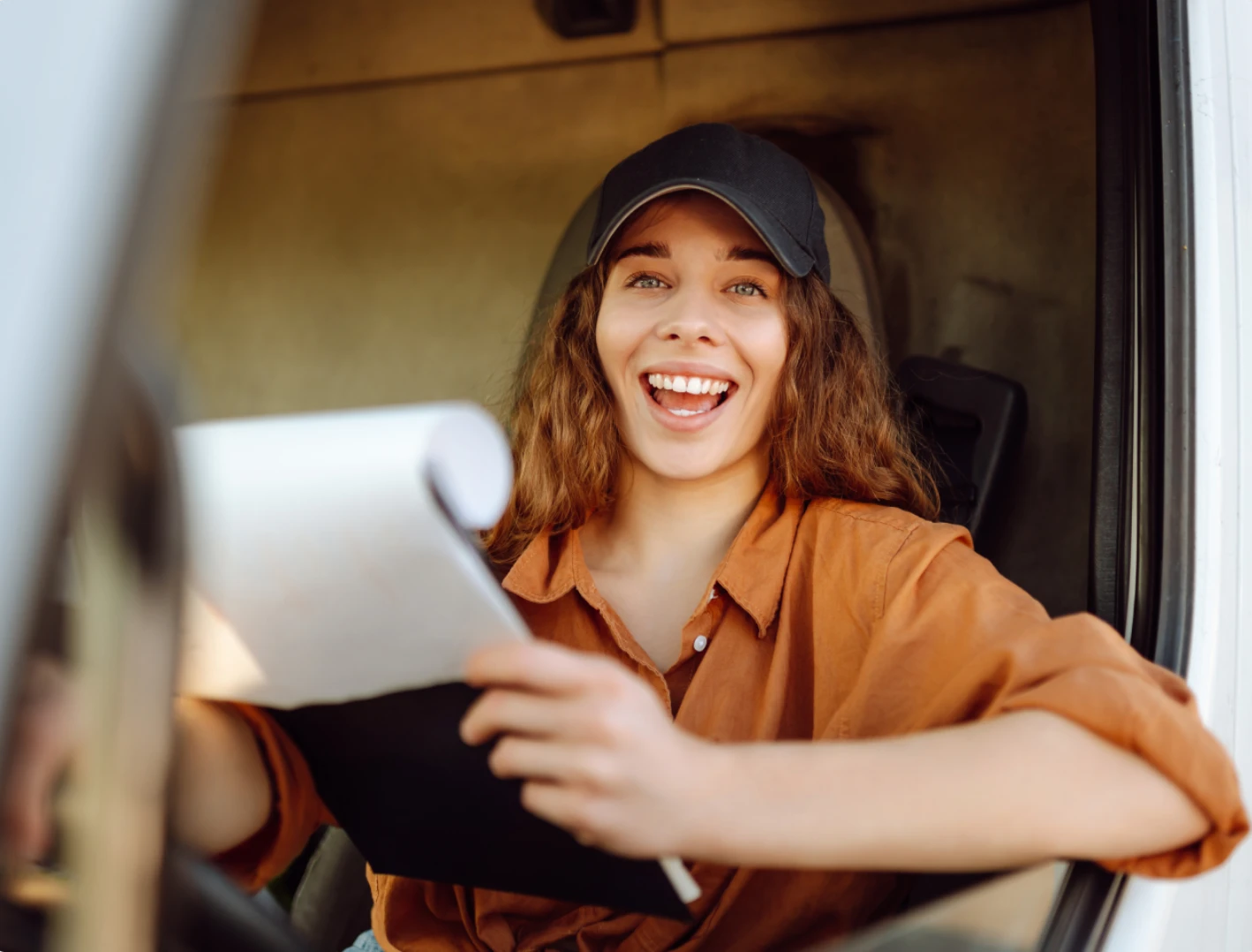 A smiling driver leaning out of a truck window holding a document, conveying the ease and low risk of switching with no contract.